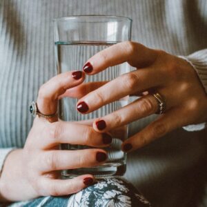 Frau hat ein Wasserglas in den Händen.